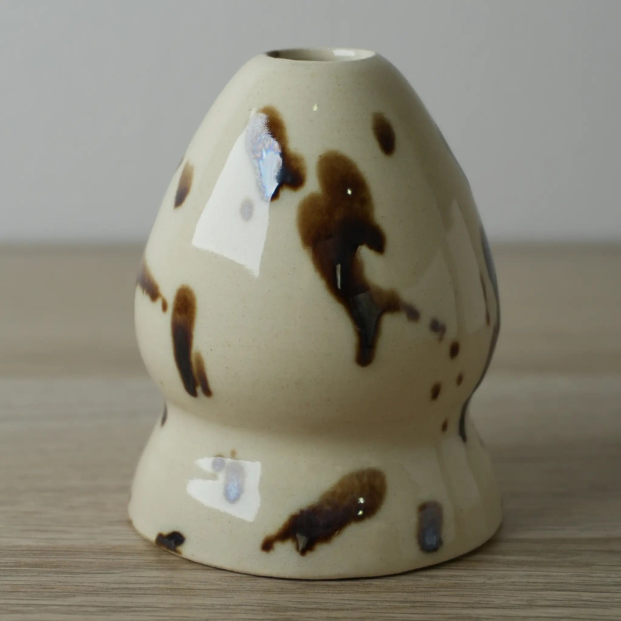 Elemento del set cerámica Ushi en color beige con manchas marrones sobre superficie de madera