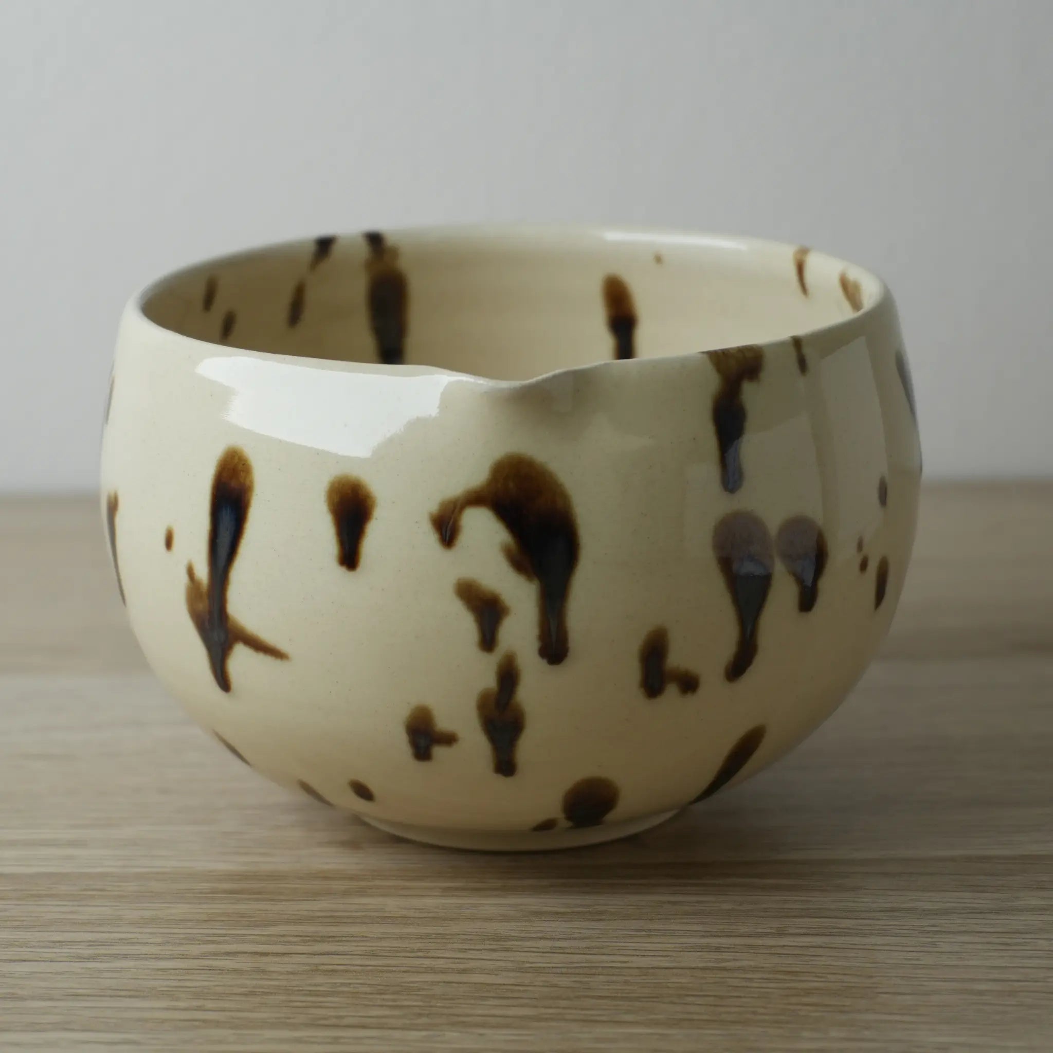 Tazón de cerámica beige con manchas marrones del set cerámica Ushi sobre superficie de madera